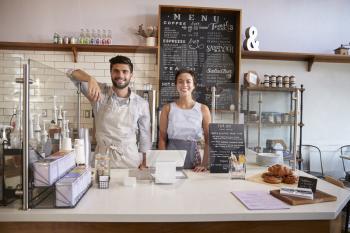 Couple ready to serve behind the counter of a coffee shop
