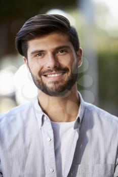 Vertical portrait of bearded young man sitting outside