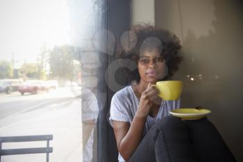 Young black woman sitting beside a window in a cafe