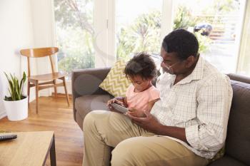 Grandfather And Granddaughter At Home Using Digital Tablet