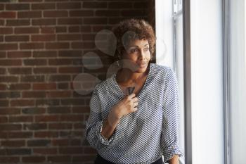 Thoughtful Mature Businesswoman Looking Out Of Office Window