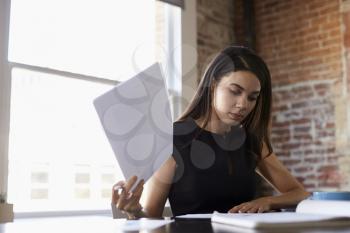 Businesswoman Making Notes On Document In Office