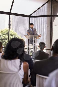 Hispanic man presents business seminar to audience, vertical