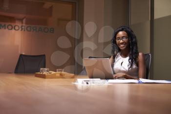 Young black woman working late in office smiling to camera