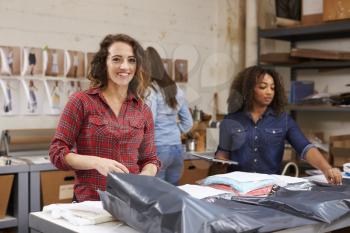 Team packing orders for distribution, woman smiles to camera