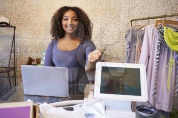 Assistant at clothing store shows computer used for payment