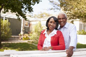 Senior black couple look to camera outside their new house