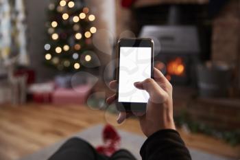 Man Using Mobile Phone In Room Decorated For Christmas