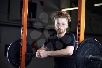 Portrait Of Young Man In Gym Lifting Weights On Barbell