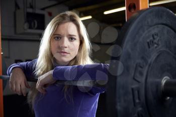 Portrait Of Young Woman In Gym Lifting Weights On Barbell