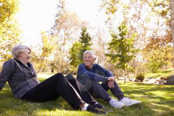 Senior Couple Resting After Exercising In Park Together