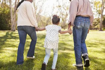 Grandparents And Granddaughter Walking In Park Together