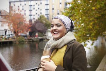 British Muslim Female With Takeaway Coffee By River In City