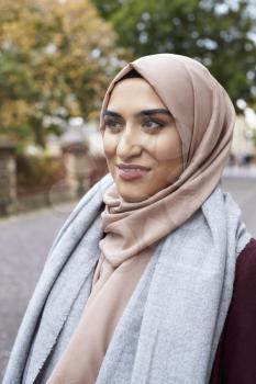 British Muslim Woman Walking On Street In Urban Environment