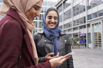 British Muslim Women Texting On Mobile Phone Outside Office