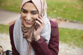 British Muslim Woman On Break Using Mobile Phone In Park