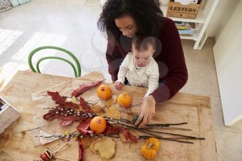 Mother And Daughter Making Autumn Decoration At Home