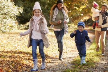 Family Running Along Path Through Autumn Countryside