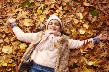 Overhead Portrait Of Girl Lying In Autumn Leaves