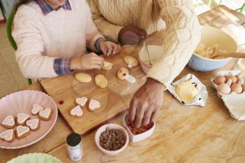 Father And Daughter Decorating Cookies At Home Together