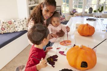 Mother And Children Making Halloween Decorations At Home