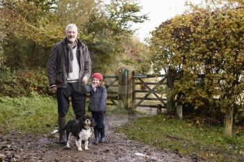 Grandfather And Granddaughter Taking Dog For Walk