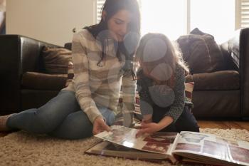 Mother And Daughter At Home Looking Through Photo Album