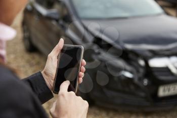 Loss Adjuster Taking Photo Of Damaged Car On Mobile Phone