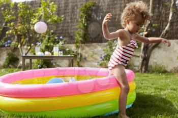 Girl Having Fun In Garden Paddling Pool