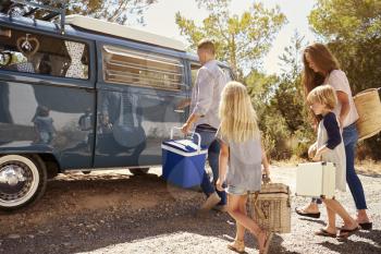 Family preparing their camper van for a road trip, side view