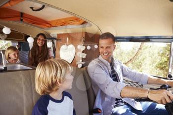 Dad driving family in a camper van, looking at his son