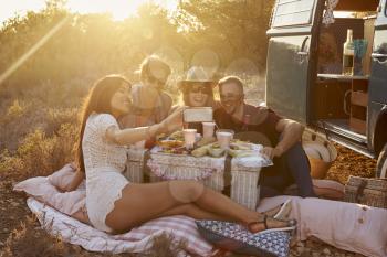 Friends taking a selfie at a picnic beside their camper van