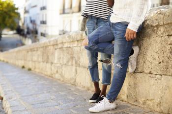 Couple leaning against a wall in Ibiza, Spain, low section