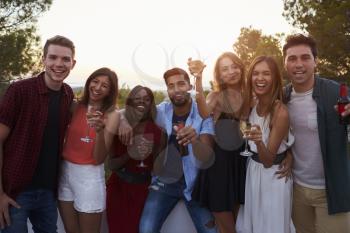 Adult friends at a party on a rooftop looking to camera