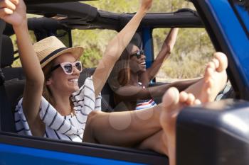 Two Female Friends Driving Open Top Car On Country Road