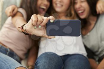 Three teenage girls taking selfie at home, focus on phone