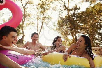 Teenage friends have fun with inflatables in a swimming pool