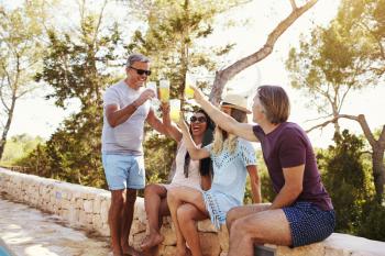 Two adult couples socialising outdoors make a toast, Ibiza