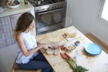 Elevated view of woman chopping vegetables at kitchen table