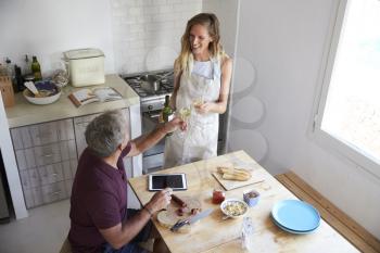 Couple drink wine and prepare food in kitchen, elevated view