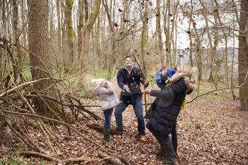 Family playing with fallen leaves in a wood, full length