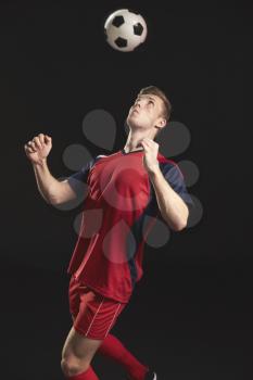 Professional Soccer Player Heading Ball In Studio
