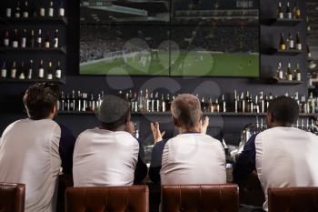 Rear View Of Male Friends Watching Game In Sports Bar