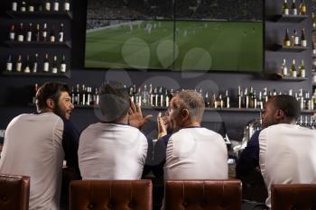 Rear View Of Male Friends Watching Game In Sports Bar