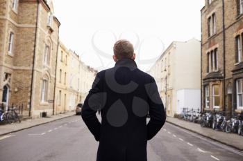 Rear View Of Man Walking Along Residential Street In Oxford