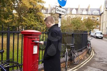 OXFORD/ UK- OCTOBER 26 2016: Man Posting Letter In Royal Mail Postboxperson,person,people,caucasian,20s,twenties,england,horizontal,autumn,fall,copy space,old fashioned, royal mail, postal, service