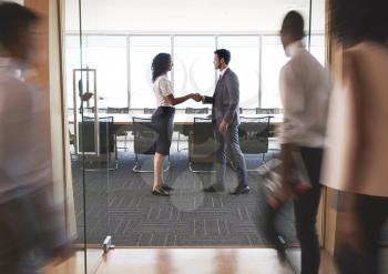 Businesspeople Shaking Hands In Entrance To Boardroom