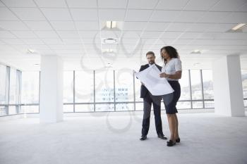 Businesspeople Meeting To Look At Plans In Empty Office