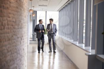 Two Businessmen Having Informal Meeting In Office Corridor