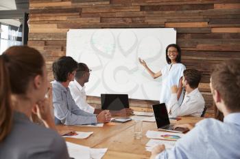Young black woman giving business presentation at whiteboard